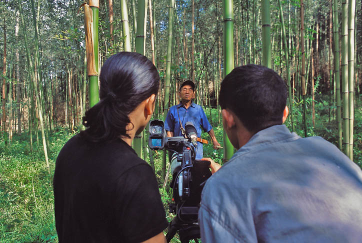 moji-riba-at-work-in-arunachal-pradesh Hage Komo gets video instructions from Moji Riba, who is enlisting local young people to capture the oral histories, languages and rituals of their tribes for his project. Komo films his father gathering bamboo in a grove outside Hari Village. (Photo courtesy Rolex Awards)